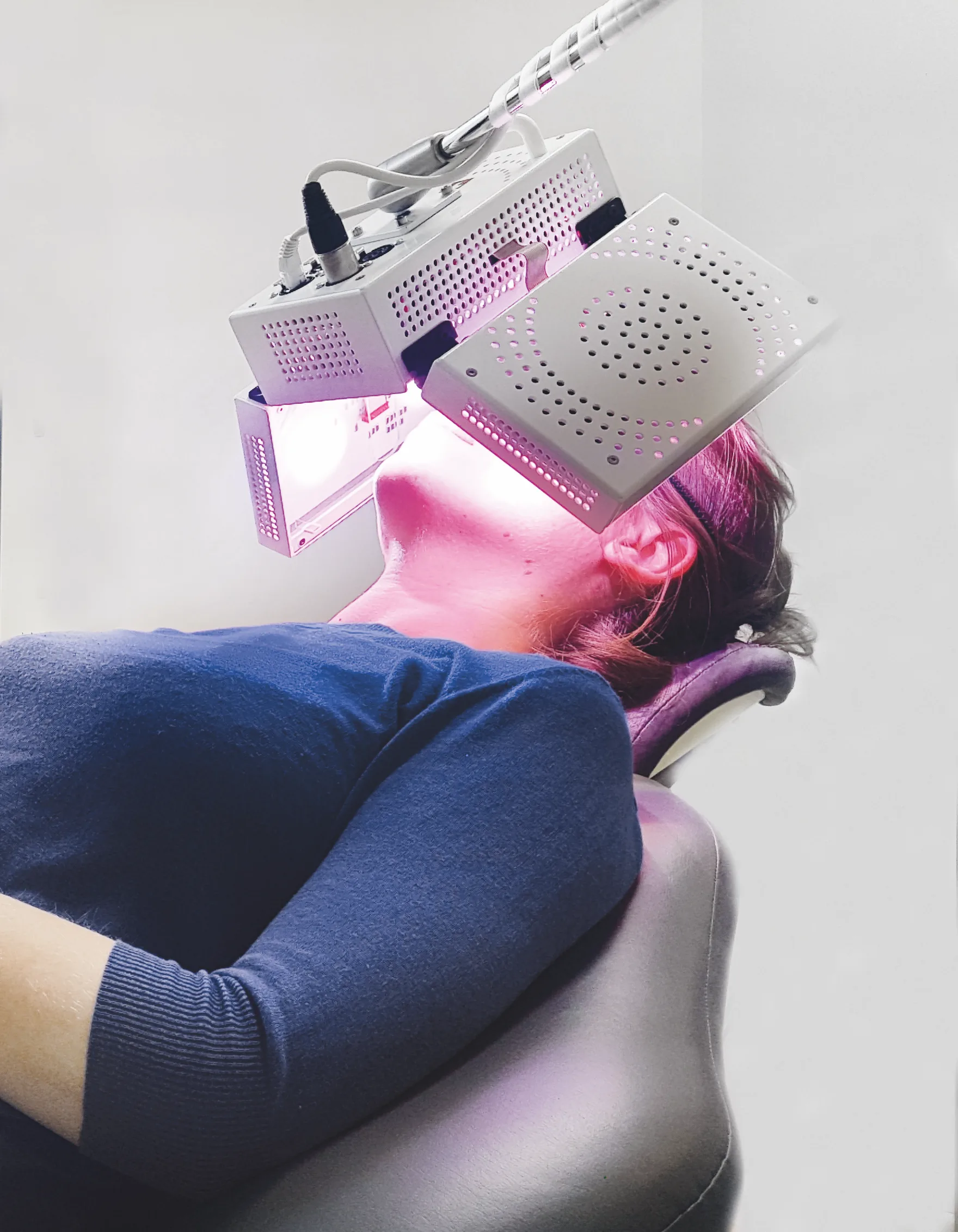 Patient reclining in a treatment chair receiving facial photobiomodulation from ATP38 light panels